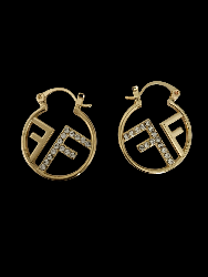 A pair of gold Fendi hoop earrings featuring the interlocking FF logo, embellished with clear crystals along the lettering, set against a solid black background.